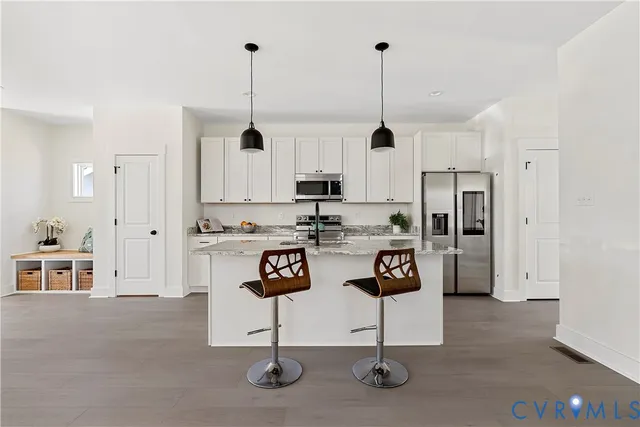 a view of kitchen with stainless steel appliances granite countertop refrigerator stove microwave and cabinets