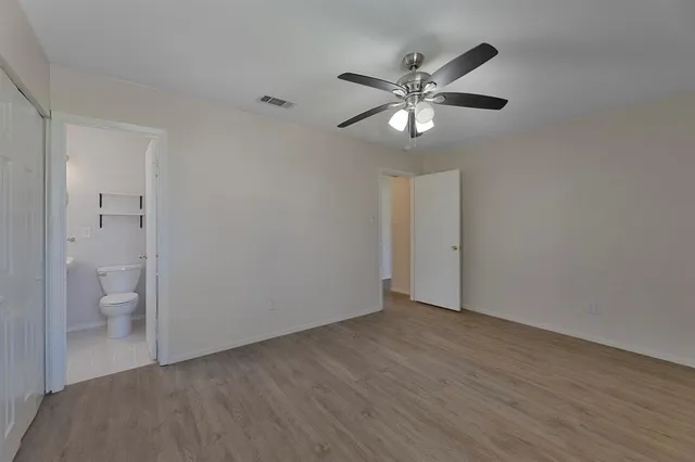 a view of an empty room with a fan and a bathroom