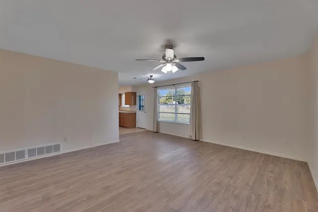 a view of an empty room with a window and wooden floor