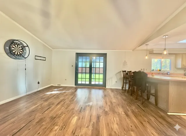 a view of an empty room with window and wooden floor