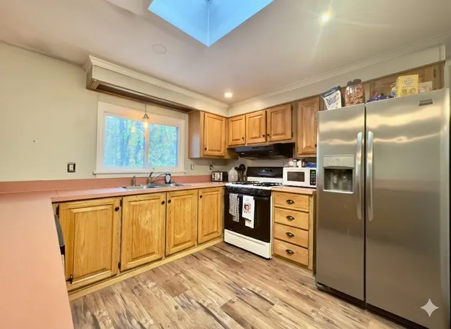 a kitchen with white cabinets stainless steel appliances a sink and a window