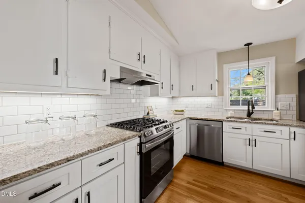 a kitchen with granite countertop white cabinets and stainless steel appliances