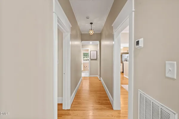 a view of a hallway with wooden floor and a bathroom