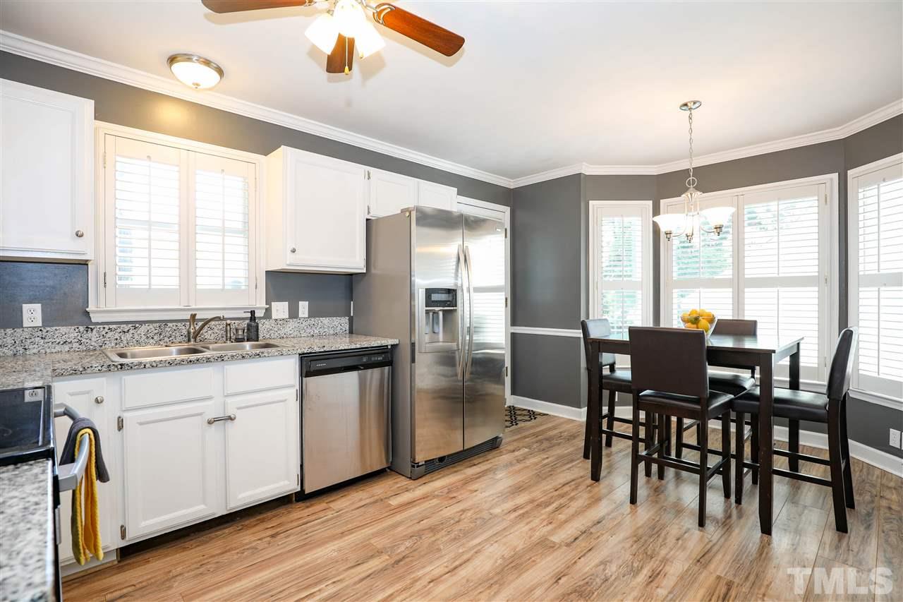 4841 Draper Road Raleigh, NC 27616 - Photo 10 of 30 a kitchen with stainless steel appliances granite countertop a stove a sink dishwasher a dining table and chairs with wooden floor