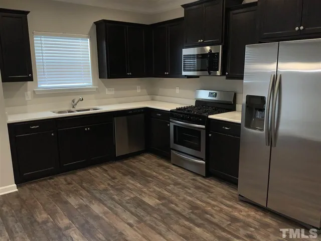 a kitchen with stainless steel appliances granite countertop a refrigerator and a sink