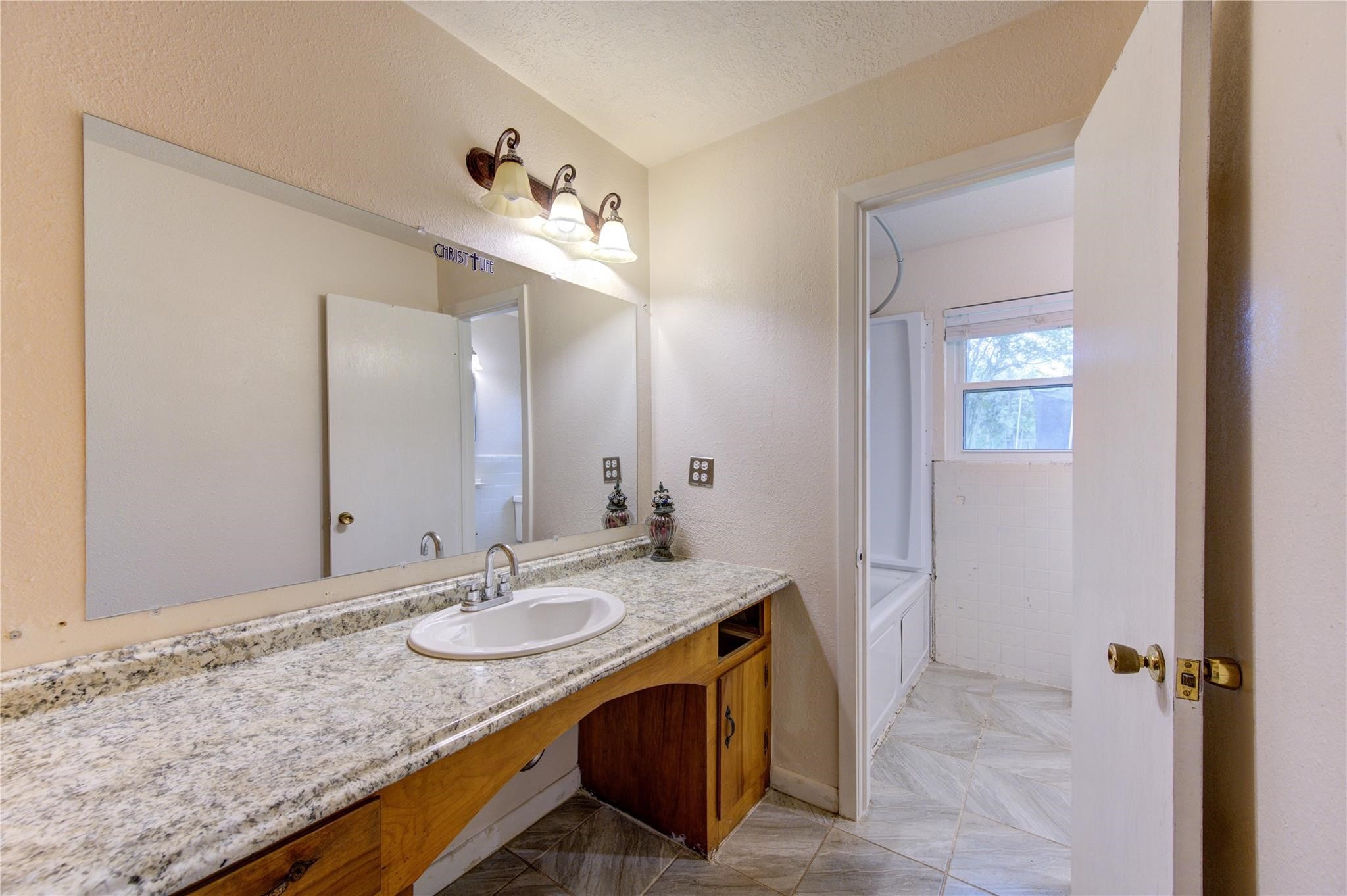1745 Stone Road Pearland, TX 77581 - Photo 23 of 31 a bathroom with a granite countertop sink and a mirror