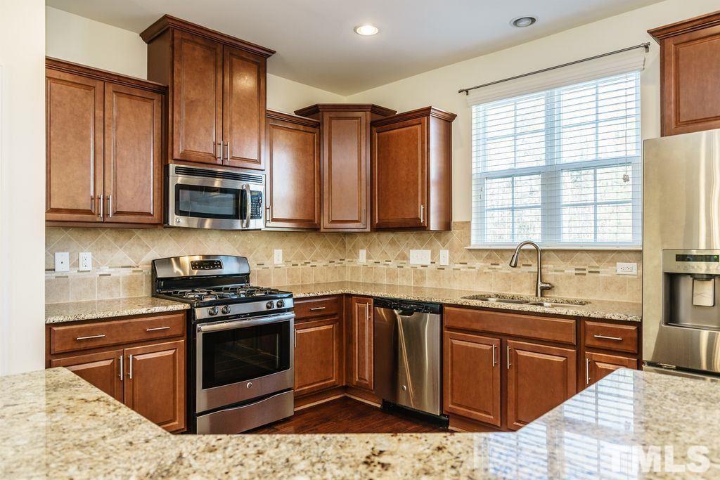 4956 Highcroft Drive Cary, NC 27519 - Photo 5 of 17 a kitchen with stainless steel appliances granite countertop wooden cabinets granite counter tops and a stove top oven