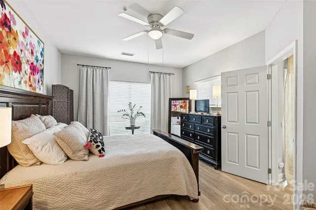 a bedroom with a bed and dresser with wooden floor