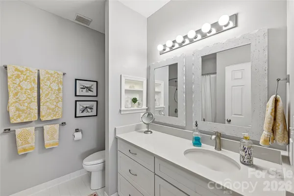 a bathroom with a granite countertop sink mirror vanity and toilet
