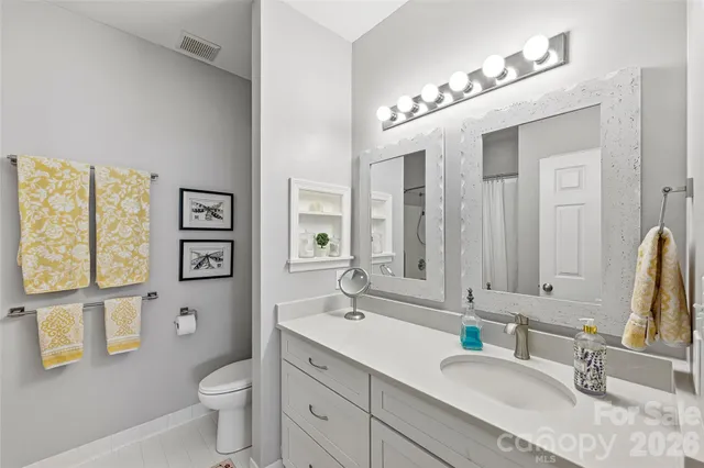 a bathroom with a granite countertop sink mirror vanity and toilet