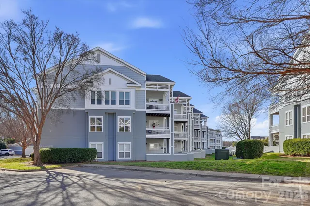 a front view of residential houses with yard and trees in the background