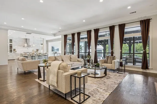 a living room with furniture large windows and wooden floor