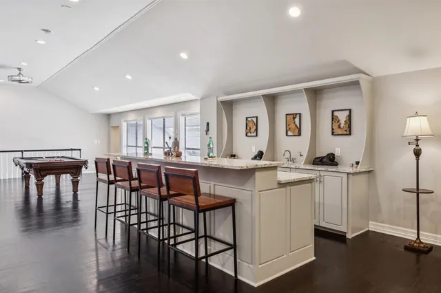 a open dining room with stainless steel appliances kitchen island granite countertop a dining table chairs and a refrigerator