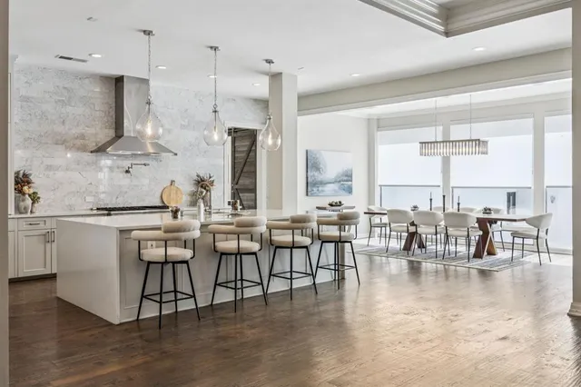 a dining hall with stainless steel appliances kitchen island granite countertop a dining table chairs and view living room