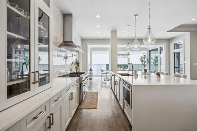 a kitchen with stainless steel appliances a stove top oven a sink a center island and living room view