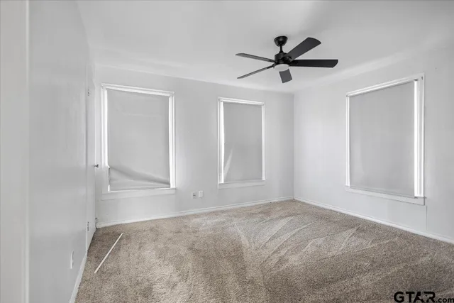 a view of empty room with wooden floor and ceiling fan
