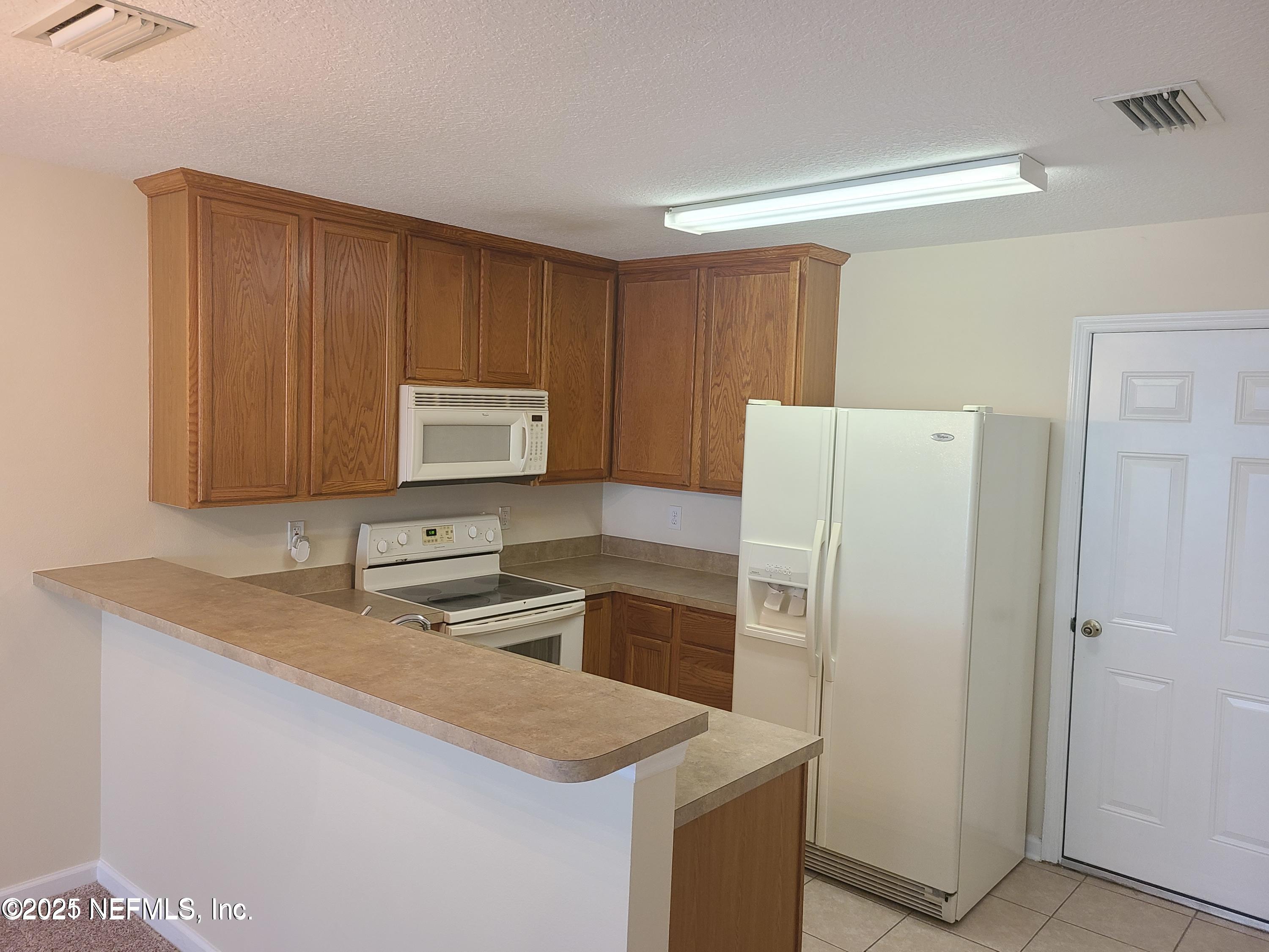 1500 Calming Water Drive, Unit 5703 Fleming Island, FL 32003 - Photo 3 of 17 a kitchen with a sink a stove a refrigerator and a microwave