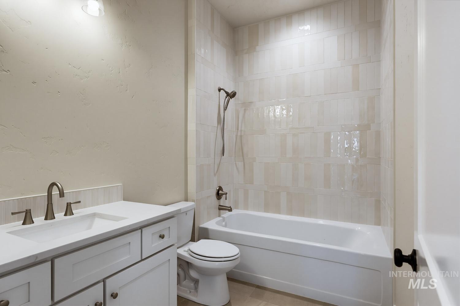 5054 Heritage Drive Marsing, ID 83639 - Photo 24 of 38 Bathroom featuring a built-in tub with a shower fixture, wall-mounted light fixture, white vanity with shaker-style cabinetry, white countertop, and a brushed nickel faucet