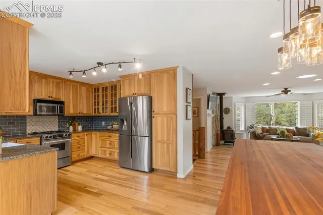 a kitchen with stainless steel appliances granite countertop a refrigerator a stove top oven a sink dishwasher and wooden floor