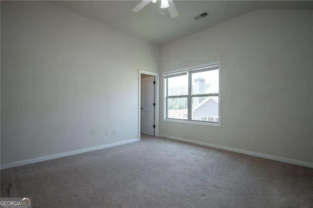 an empty room with a window and a chandelier fan
