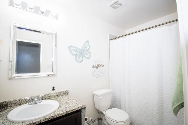 a bathroom with a granite countertop sink toilet and a mirror