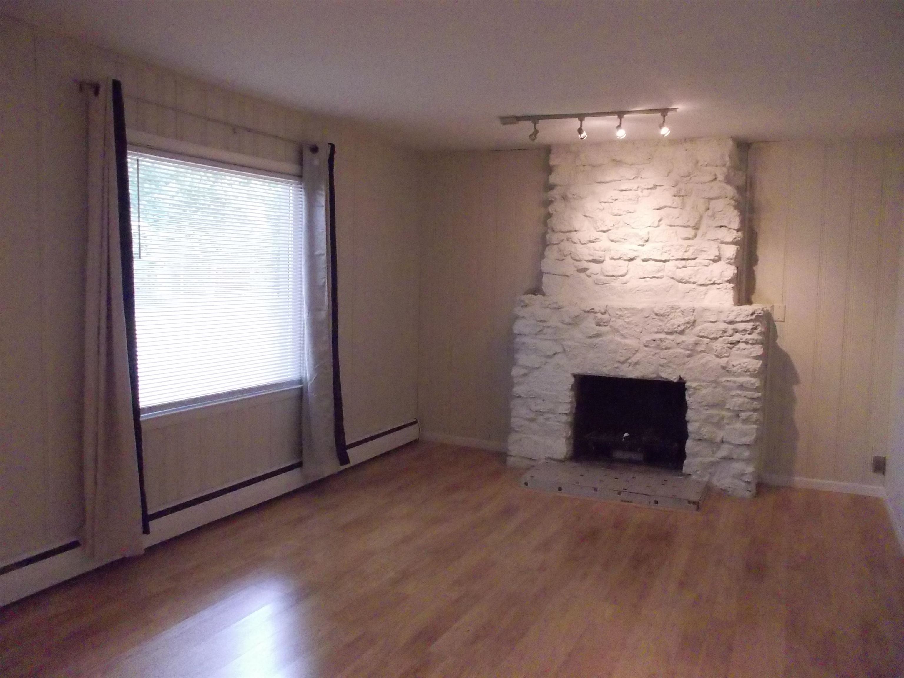 724 Taft Road Rockford, IL 61109 - Photo 5 of 19 an empty room with wooden floor fireplace and windows