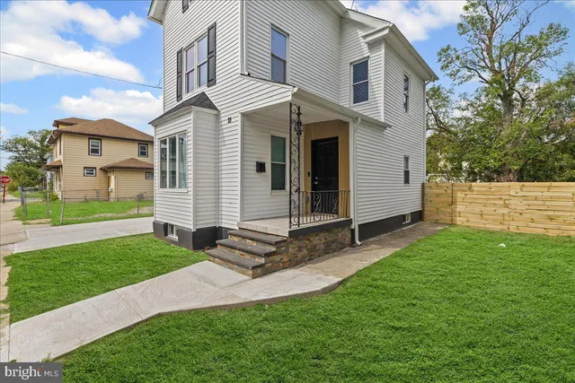 a view of a white house next to a yard with big trees