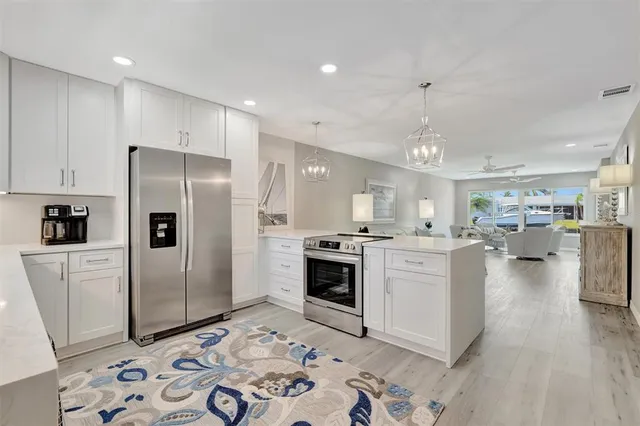 a kitchen with stainless steel appliances kitchen island granite countertop a refrigerator and a sink