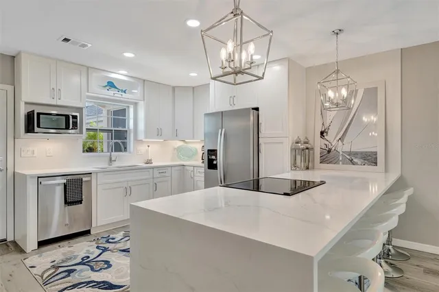 a kitchen with stainless steel appliances granite countertop a sink a stove a refrigerator cabinets and chairs