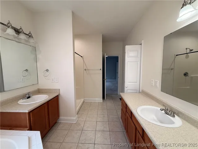 a spacious bathroom with a double vanity sink a mirror and a bathtub