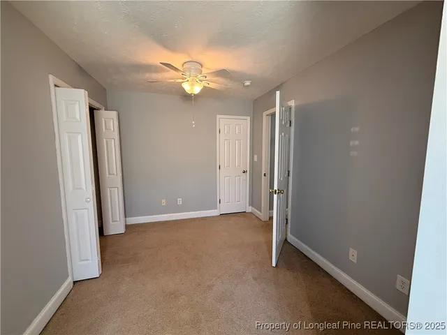 an empty room with closet and a ceiling fan