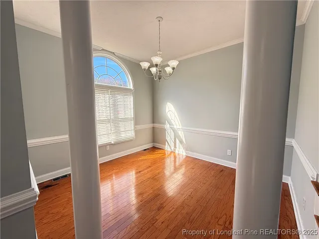 a view of a livingroom with wooden floor a ceiling fan and windows