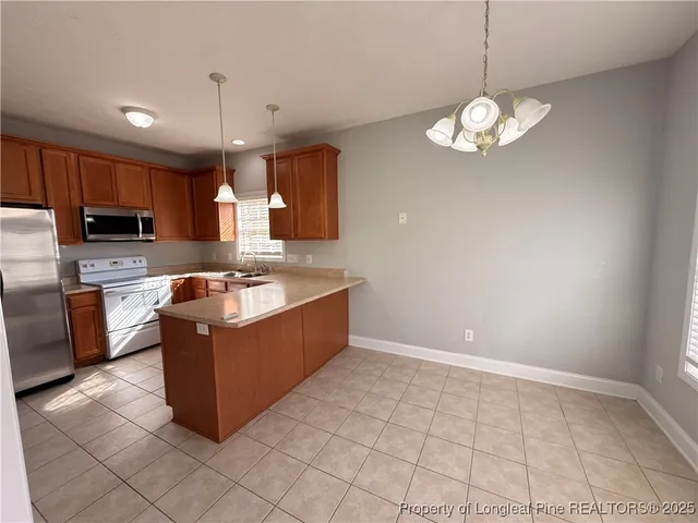 a large kitchen with kitchen island granite countertop a sink a counter top space a stove and cabinets