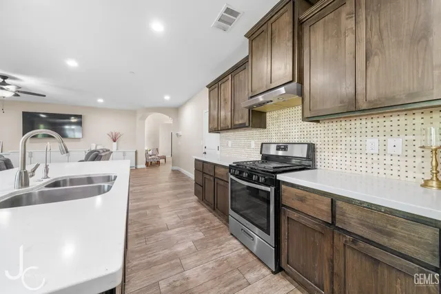 a kitchen with stainless steel appliances granite countertop a sink stove and cabinets