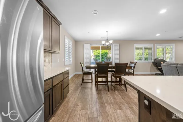 an open kitchen with granite countertop a refrigerator a stove dining table and chairs