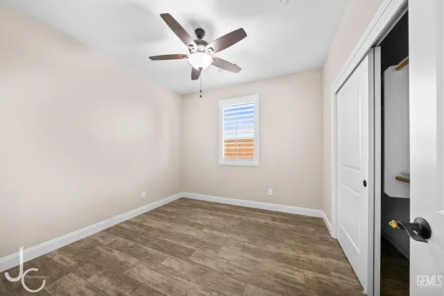 an empty room with a window and ceiling fan