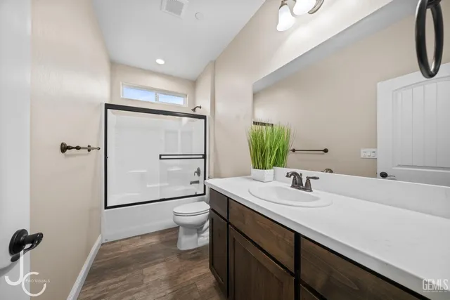 a bathroom with a granite countertop sink a toilet and shower