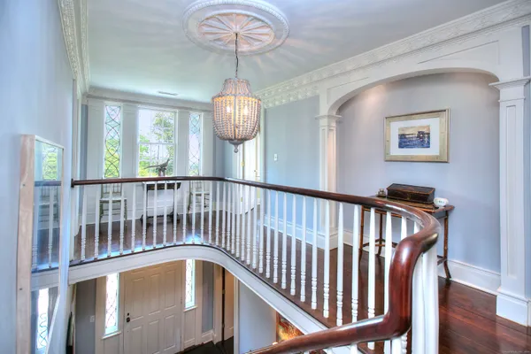a view of a hallway with wooden floor and chandelier