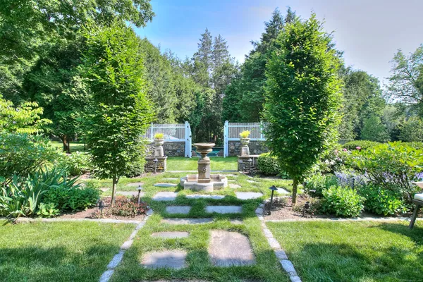 a view of a house with a big yard potted plants and large tree