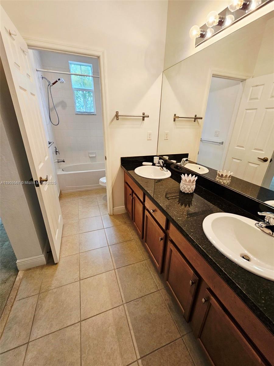 809 Southwest 147th Avenue, Unit 1401 Pembroke Pines, FL 33027 - Photo 12 of 19 a bathroom with a double vanity sink a toilet and a mirror