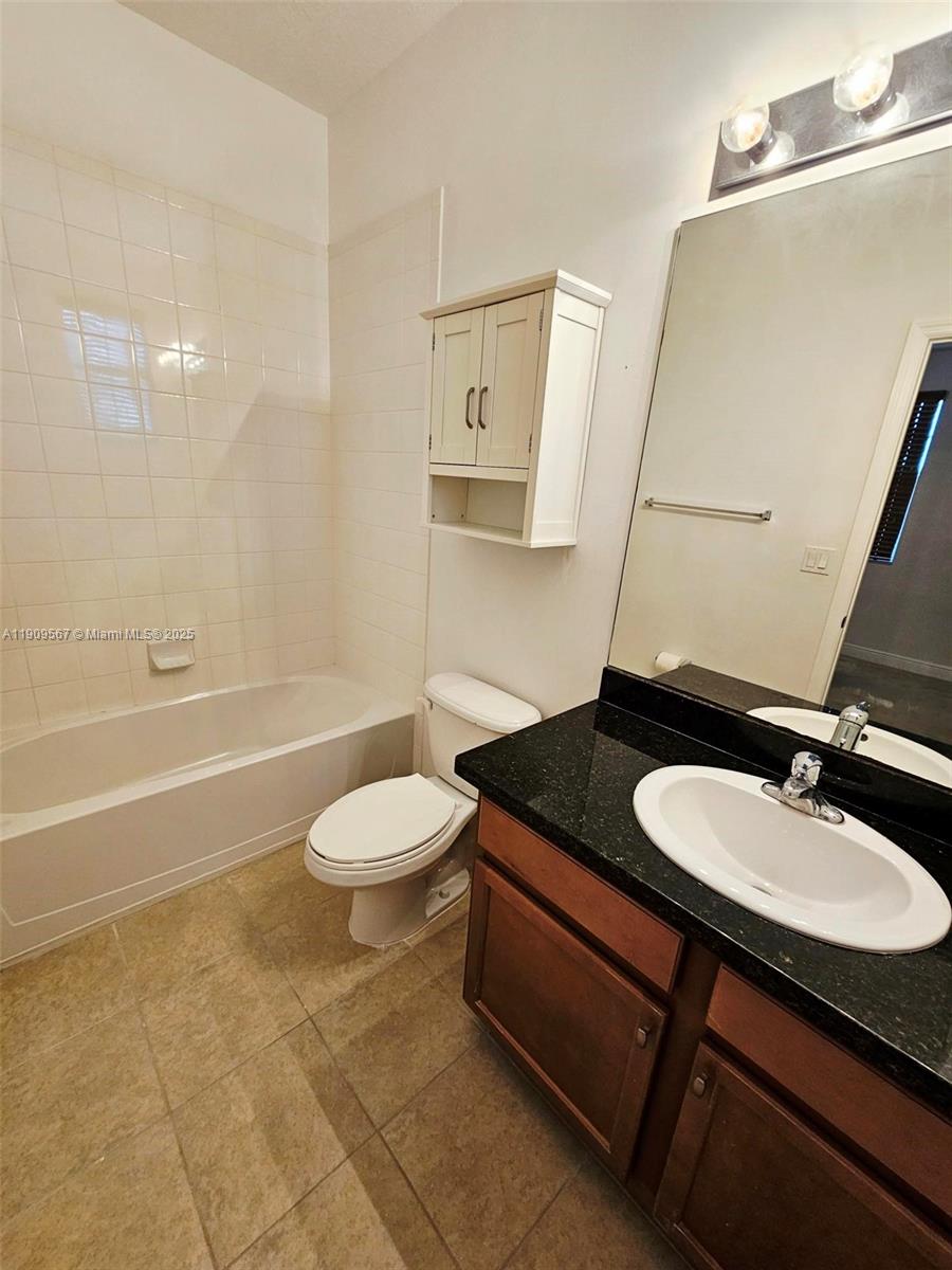809 Southwest 147th Avenue, Unit 1401 Pembroke Pines, FL 33027 - Photo 10 of 19 a bathroom with a granite countertop sink toilet a mirror and shower