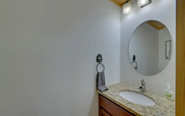 a bathroom with a granite countertop sink a light fixture and a mirror