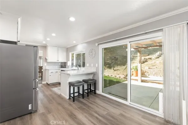 a kitchen with stainless steel appliances granite countertop a refrigerator a sink a stove and white cabinets with wooden floor