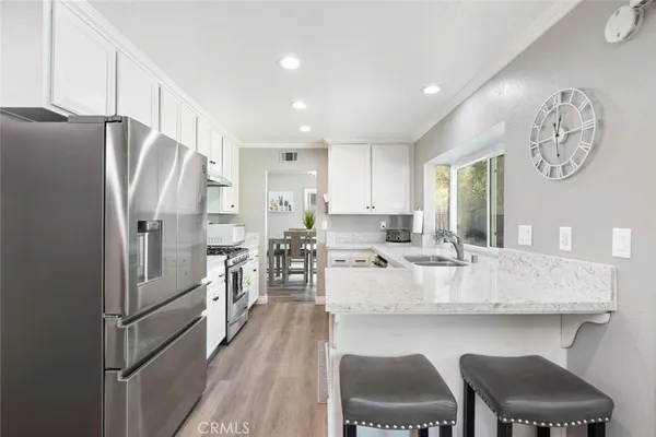 a kitchen with stainless steel appliances granite countertop a table chairs a refrigerator and cabinets