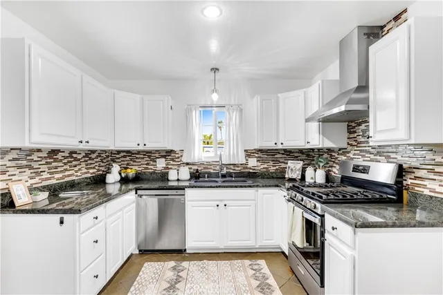 a white kitchen with granite countertop stainless steel appliances