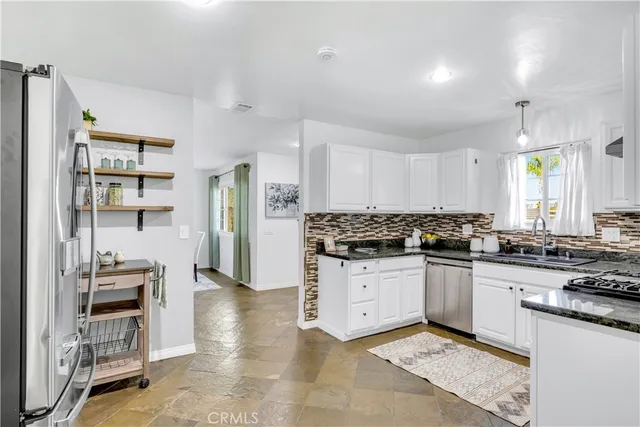 a kitchen with stainless steel appliances granite countertop a stove top oven a sink a counter space and cabinets
