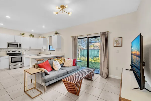 a living room with stainless steel appliances furniture and a flat screen tv