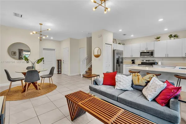 a living room with furniture kitchen view and a chandelier