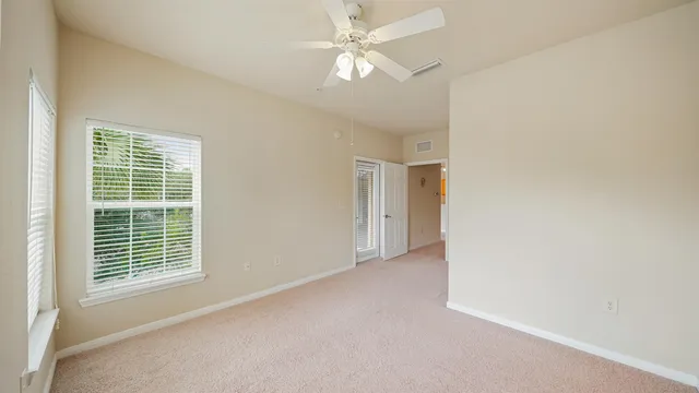 an empty room with windows and fan