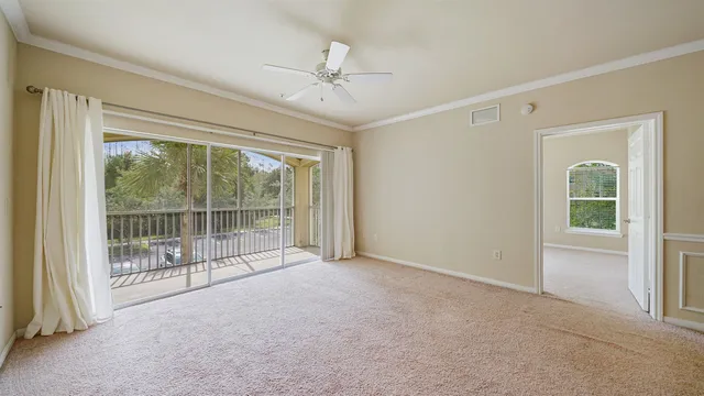 an empty room with chandelier fan and windows